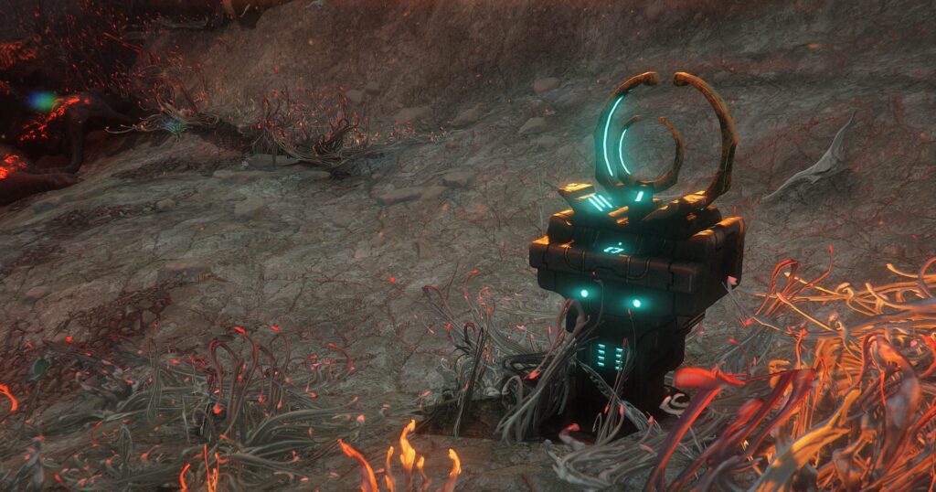 A screenshot showing a small Orokin device known as a Purifier, consisting of a boxy base made of dark stone with two ring-shapped antennae oriented vertically. The device has gold accents and glowing blue lights. It is planted in the gray rocky surface of Deimos' Cambion Drift, and Infested grass-like growths cover the ground. Screenshot by GrayArchon.